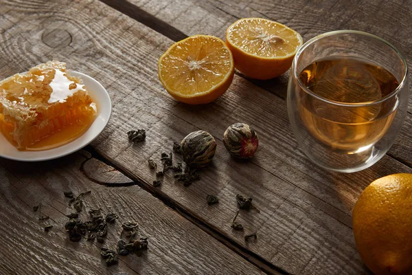 Glas chinesischen blühenden Tee, Zitronen und Honigwaben auf Holztisch — Stockfoto