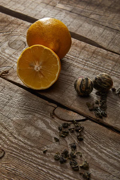 Свежие лимоны и цветущие чайные шарики на деревенском деревянном столе — стоковое фото