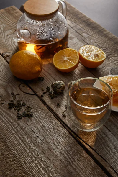 Citrons, boules de thé et théière transparente avec verre de thé chinois traditionnel en fleurs sur une surface en bois — Stock Photo