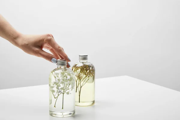 Vue recadrée de femme touchant bouteille avec shampooing bio sur table blanche — Photo de stock