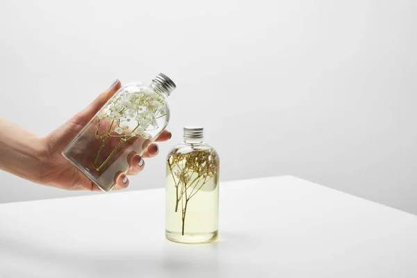 Vue recadrée de la femme tenant bouteille avec shampooing biologique sur table blanche — Photo de stock