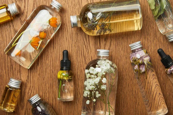 Vue du dessus des bouteilles transparentes avec des produits de beauté bio sur fond en bois — Photo de stock