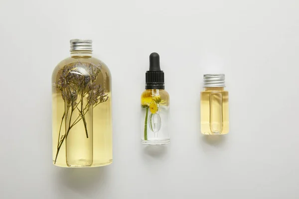 Vista superior de botellas transparentes con productos de belleza natural sobre fondo gris - foto de stock
