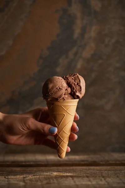 Ausgeschnittene Ansicht einer Frau mit Schokoladeneisbecher über Holztisch — Stockfoto