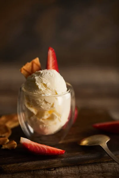 Selective focus of delicious ice cream with strawberry and piece of waffle on cutting board — Stock Photo