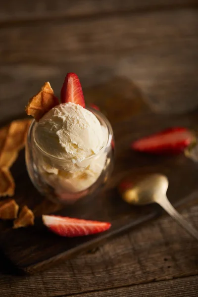 Selective focus of delicious ice cream with strawberry and piece of waffle on chopping board — Stock Photo