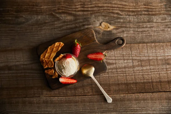 Top view of ice cream in glass with strawberries and pieces of waffle on cutting board on table with copy space — Stock Photo