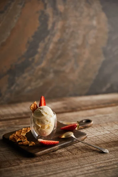 Delicioso helado en vidrio con fresas y trozos de waffle en la tabla de cortar en la mesa con espacio para copiar - foto de stock