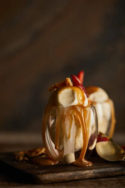 Leckeres Eis mit Karamell im Glas auf Holzschneidebrett — Stockfoto