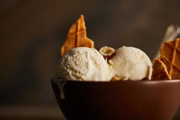 Messa a fuoco selettiva di deliziosi misurini di gelato con pezzi di cialda e nocciole in ciotola sul tavolo — Foto stock