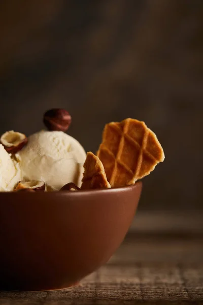 Selective focus of delicious ice cream with pieces of waffle and hazelnuts in bowl — Stock Photo