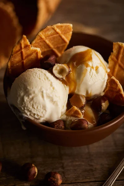 Delicious ice cream with pieces of waffle, caramel and hazelnuts in bowl — Stock Photo