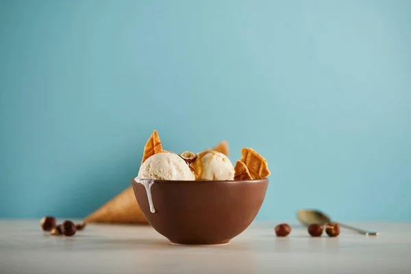 Ciotola di delizioso gelato con pezzi di cialda su blu con copyspace — Foto stock