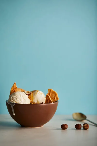 Bowl of delicious scoops of ice cream with pieces of waffle on blue with copy space — Stock Photo