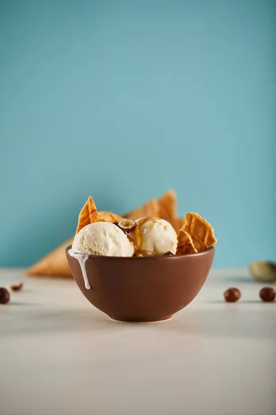 Bol de délicieuse crème glacée avec des morceaux de gaufre et de carmel sur bleu avec espace de copie — Photo de stock