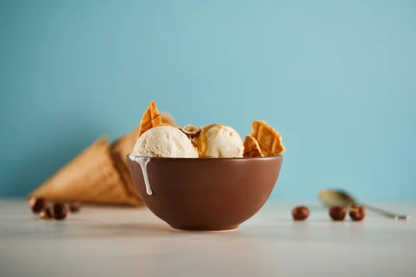 Selektiver Fokus der Schüssel mit leckeren Eiskugeln mit Waffelstücken auf blau — Stockfoto