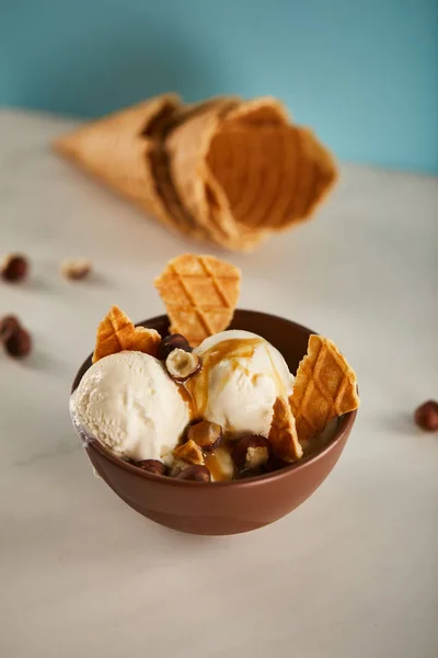 Чаша вкусного мороженого с карамелью, фундуком и кусочками вафли — стоковое фото