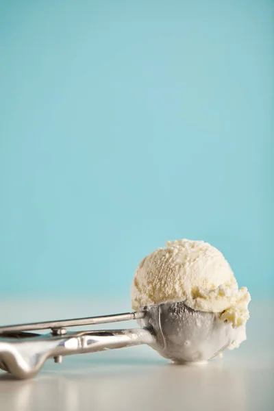 Ice cream scoop in metal spoon on blue with copy space — Stock Photo