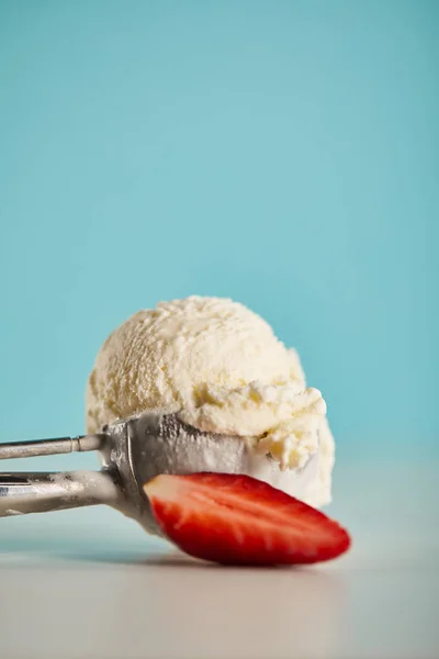 Scoop of ice cream in spoon and strawberry on blue with copy space — Stock Photo
