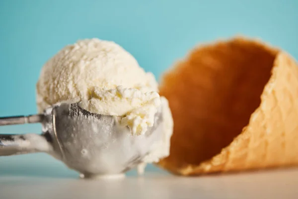 Délicieuse cuillère à crème glacée et cône de gaufre sur bleu — Photo de stock