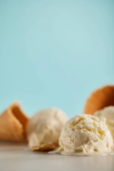 Selective focus of ice cream scoops and waffle cones on blue with copy space — Stock Photo