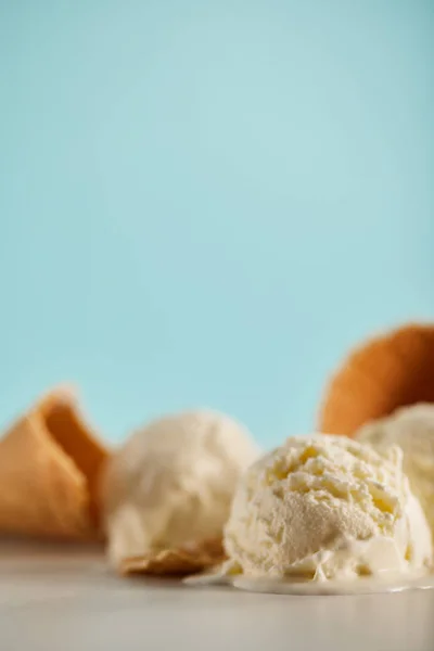 Foyer sélectif de boules de crème glacée et de cônes de gaufres sur bleu avec espace de copie — Photo de stock