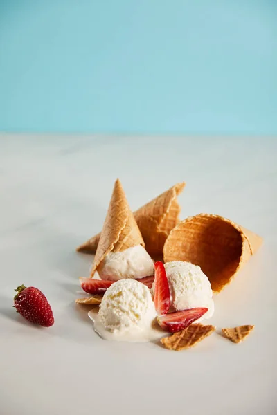 Cônes de gaufres et délicieuse crème glacée fondante aux fraises sur fond gris avec espace de copie — Photo de stock