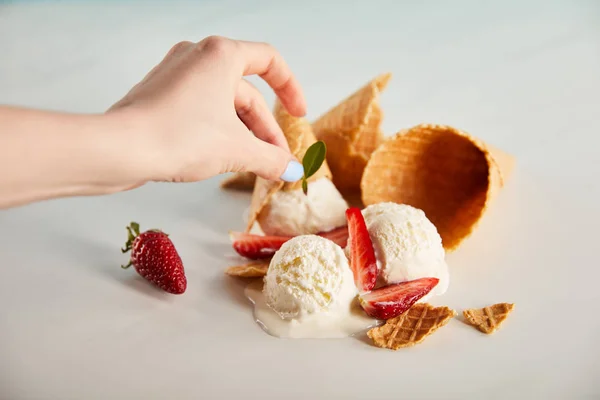 Vista ritagliata della donna che decora delizioso gelato fondente con erbe su grigio — Foto stock