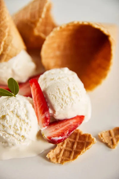 Close up view of waffle cones and delicious melting ice cream with strawberries on grey — Stock Photo