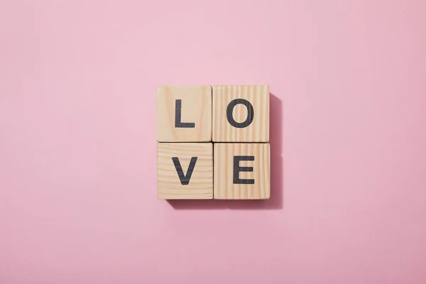 Top view of wooden cubes with letters on pink surface — Stock Photo