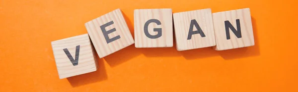 Panoramic shot of wooden cubes with letters on orange surface — Stock Photo