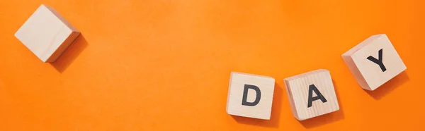 Panoramic shot of wooden cubes with letters on orange surface — Stock Photo