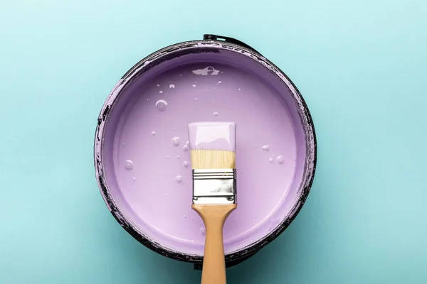 Top view of bucket with purple paint and brush on blue — Stock Photo