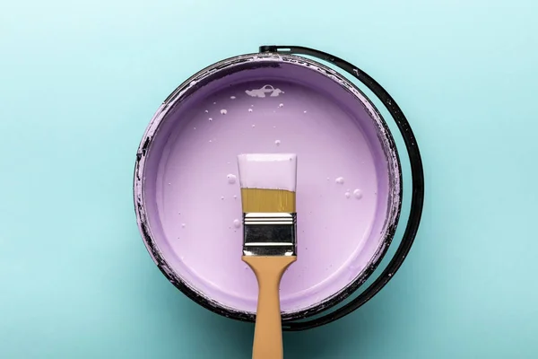 Вид зверху відра з фіолетовою фарбою і пензлем на синьому — стокове фото
