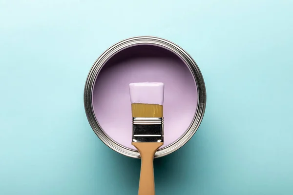 Top view of tin with purple paint and brush on blue surface — Stock Photo