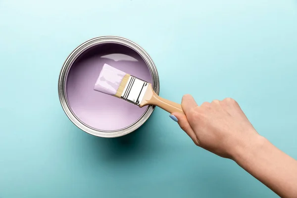 Partial view of woman with brush and tin of purple paint on purple surface — Stock Photo