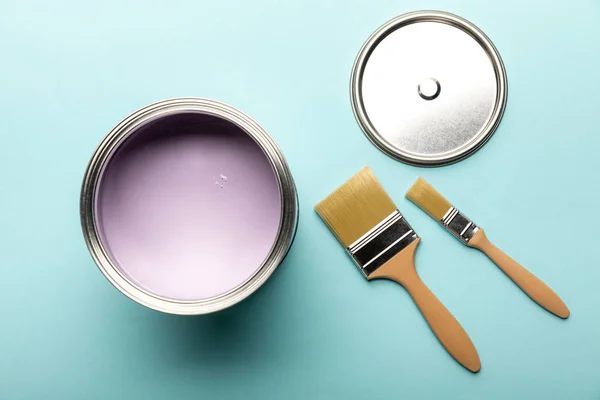 Top view of tin with purple paint and brushes on blue surface — Stock Photo