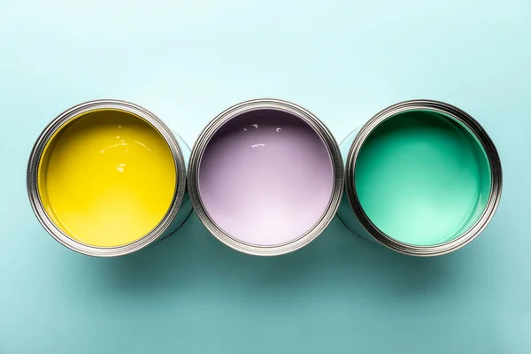 Vista superior de tres latas con pinturas sobre superficie azul - foto de stock