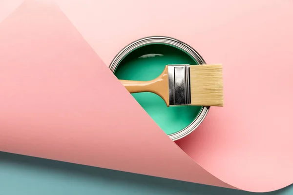 Vista superior de estaño de pintura verde y pincel sobre superficie rosa - foto de stock