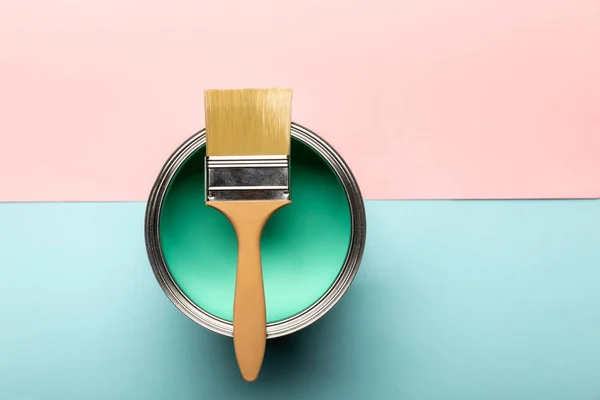 Top view of tin on green paint and brush on pink and blue surface — Stock Photo