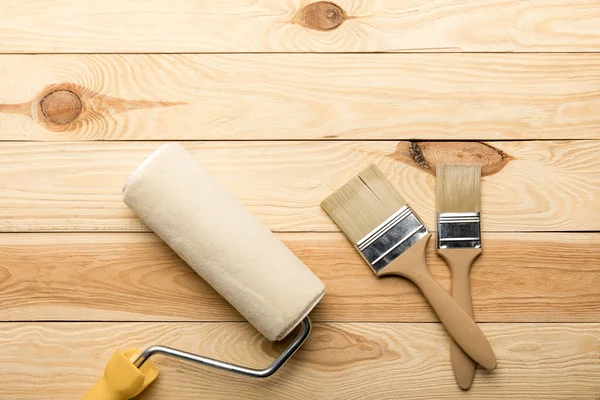 Paint roller and two brushes on wooden surface — Stock Photo