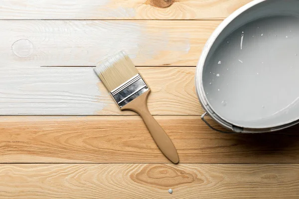 Vista superior del pincel y cubo de pintura blanca en la superficie de madera - foto de stock