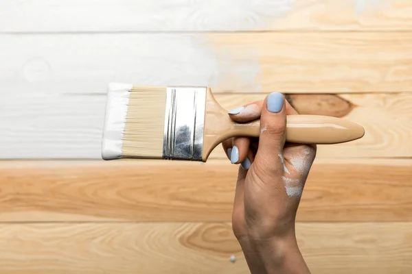 Обрізаний вид жінки, що малює дерев'яну поверхню в білому — стокове фото