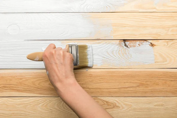 Cropped view of woman painting wooden surface in white — Stock Photo