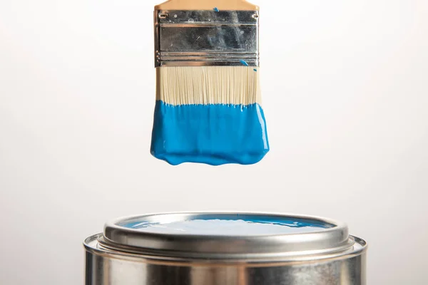Tin with blue paint and brush on white — Stock Photo