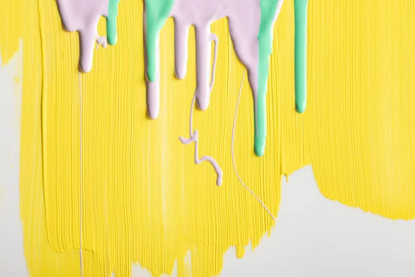 Painted yellow background with flowing green and purple paints — Stock Photo