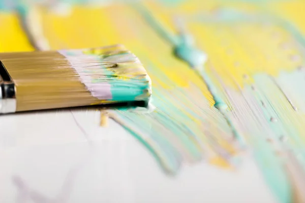 Selective focus of brush and colorful brushstrokes on white surface — Stock Photo