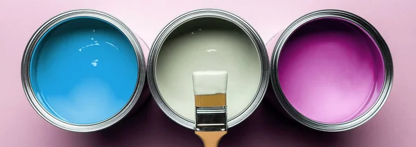 Panoramic shot of brush and cans with paints on pink surface — Stock Photo