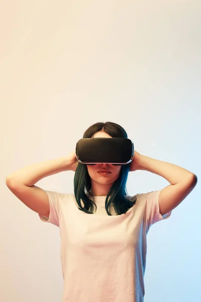 Morena mujer joven con auriculares de realidad virtual en beige y azul - foto de stock