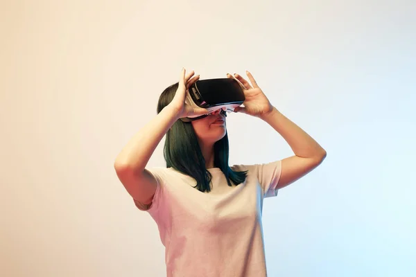 Attraente giovane donna toccando realtà virtuale auricolare su beige e blu — Foto stock